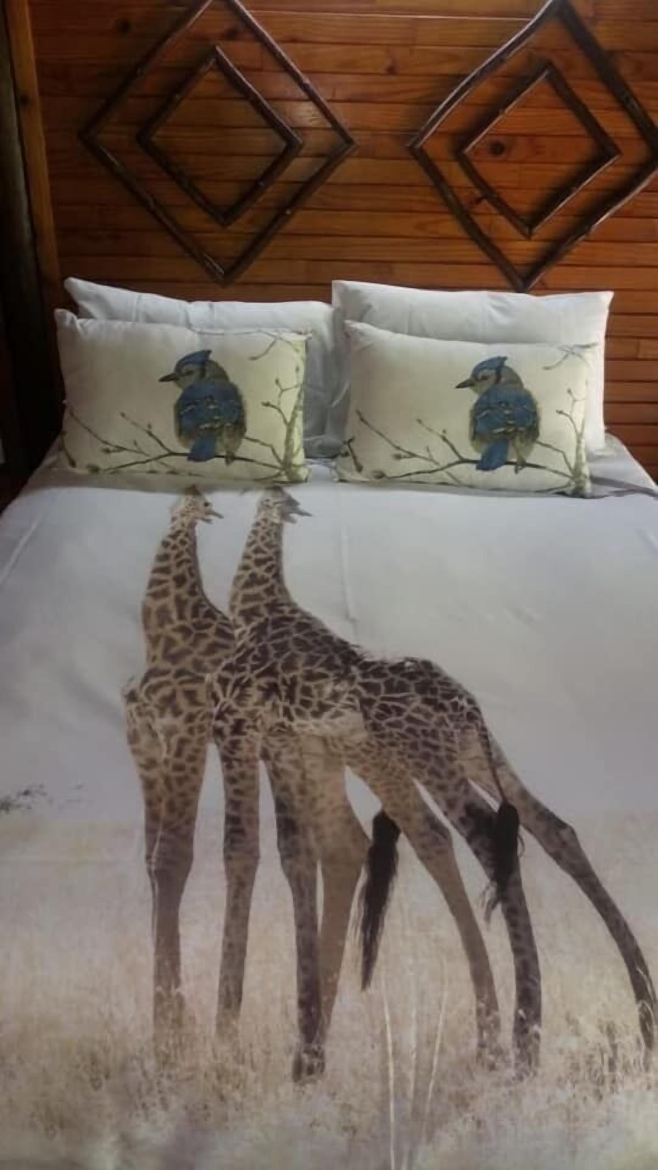Un lit avec une couvre-lit à motifs de girafe et deux oreillers à motifs d’oiseaux.