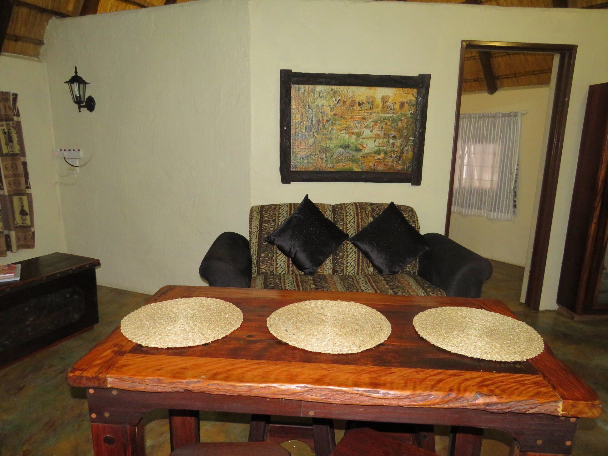 A living room with a wooden table, patterned sofa, and a painting on the wall.