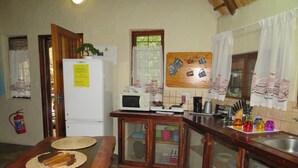 Een kleine keuken met een houten tafel, een koelkast, een magnetron en een fornuis.