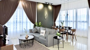 Un salon moderne avec un canapé gris, une table basse et un coin repas comprenant des chaises et une table.