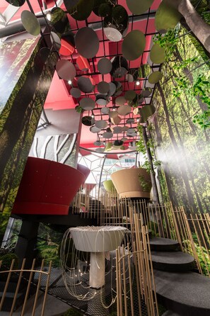 A modern interior with a unique ceiling design, a central table, and a staircase.