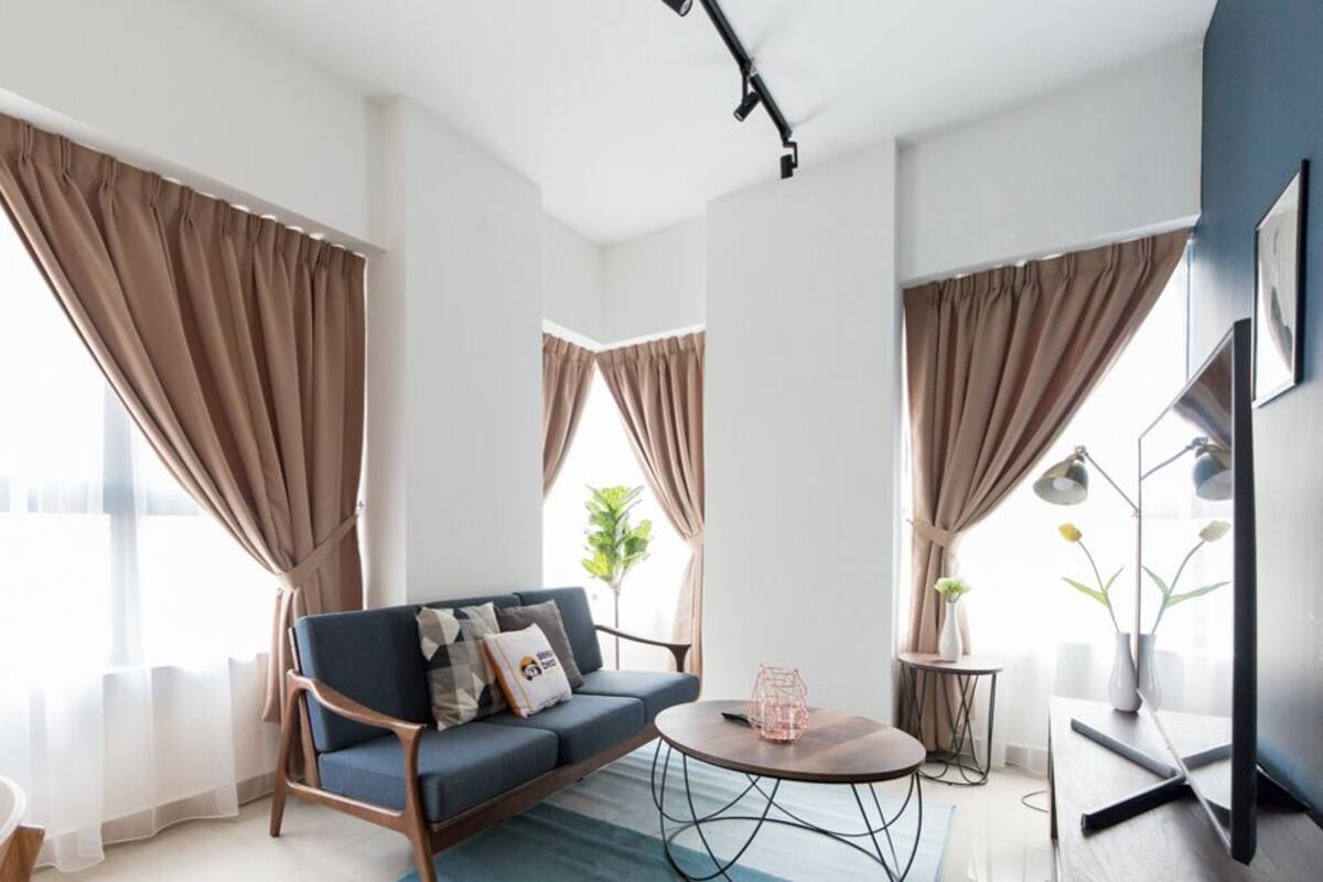 A modern living room with a sofa, coffee table, and curtains.