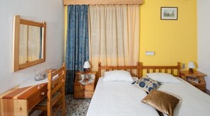 Una camera da letto con un letto, comodini in legno, una scrivania e una sedia.