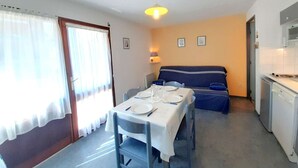 Un espace de vie compact comprenant un coin repas, une kitchenette et un canapé.