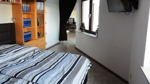 Een slaapkamer met een bed, een boekenkast, een televisie en een raam.