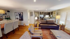Cozy living room with leather sofa, dining table for four, and a large abstract painting.