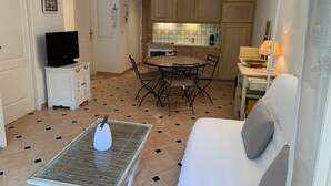 A compact living space with a dining area, kitchenette, and a sofa. - 3-room apartment with large private garden, air conditioning and parking (Cavalaire-sur-Mer)