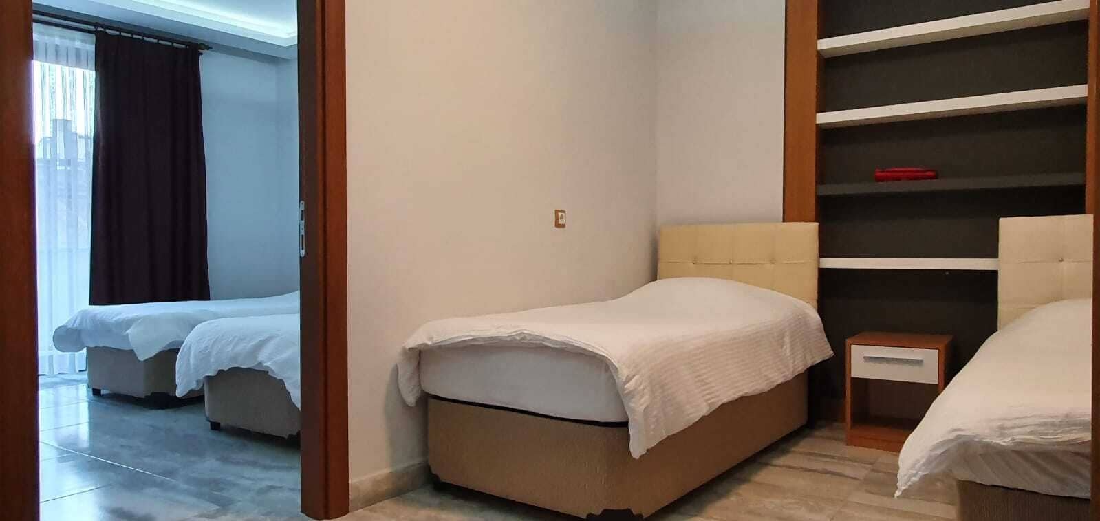 A bedroom with two beds, a wardrobe, and a small bedside table.