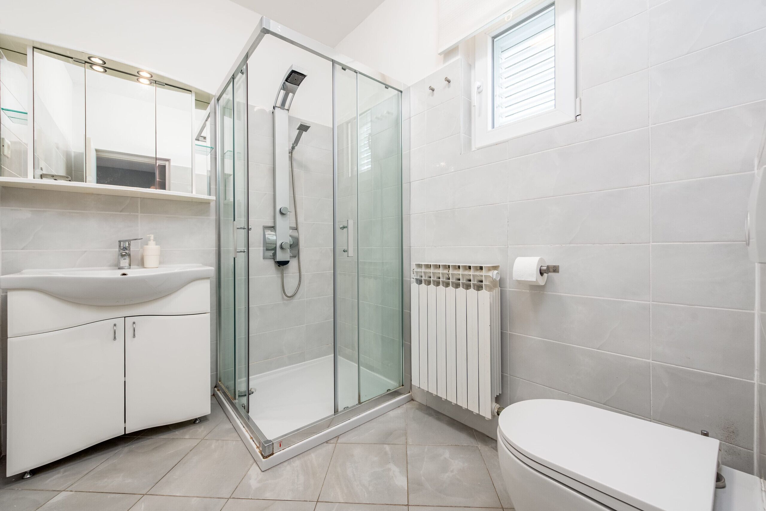 Une salle de bain moderne avec une douche à parois de verre, un lavabo blanc et des toilettes.