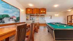 A pool table with a green felt surface, wooden chairs, and a dining table with chairs. - Villa Elder (Benkovac)