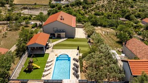A residential area with a large house featuring a swimming pool, a patio, and a playground. - Villa Elder (Benkovac)