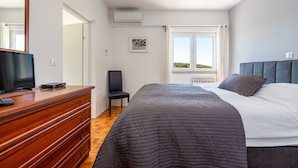 A bedroom with a bed, dresser, TV, chair, and a window with a view. - Villa Elder (Benkovac)