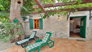 A patio with two green lounge chairs, a stone wall, and a wooden pergola. - Villa Oak (Benkovac)