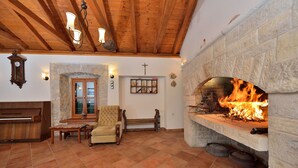 A cozy room with a stone fireplace, wooden beams, a bench, and a stone wall with a cross. - Villa Oak (Benkovac)