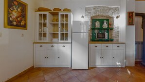 A kitchen with white cabinets, a green microwave shelf, and a stone wall. - Villa Oak (Benkovac)