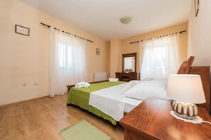 Habitación de hotel con dos camas, una mesita de noche de madera, una lámpara, un espejo y una ventana con cortinas.