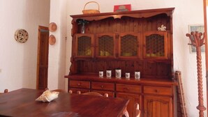 Un'area pranzo con tavolo e sedie in legno, un mobile contenitore in legno con ante in vetro e un piatto decorativo appeso al muro.