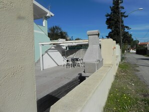 A patio area with a table and chairs, a stone chimney, and a view of the street.