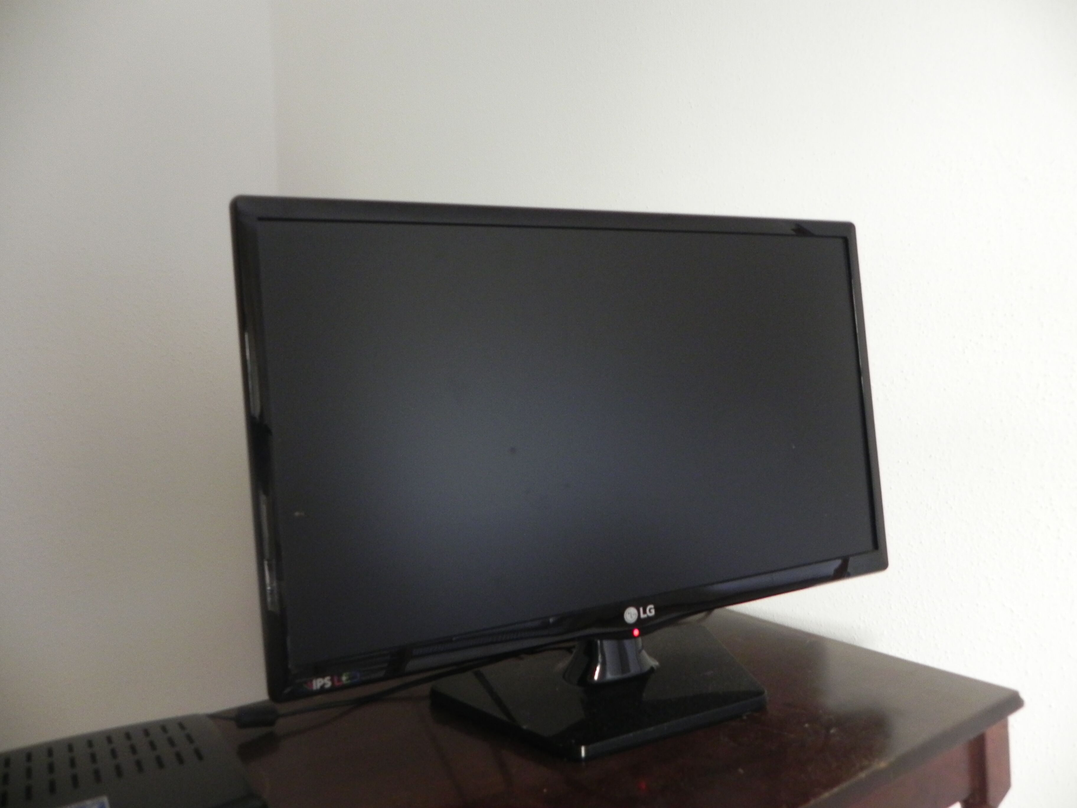 A black LG monitor on a wooden desk.