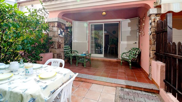 A patio area with a table set for dining, a stone wall, and a sliding glass door leading to an interior space.
