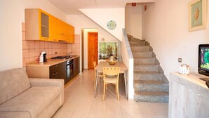 A compact living space with a kitchenette, a dining area, and a staircase leading to an upper level.