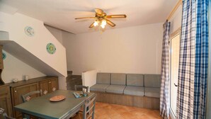Un comedor con una mesa, sillas, un ventilador de techo y un sofá.