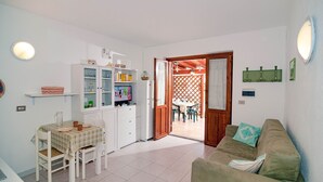 A compact living space with a dining area, kitchenette, and a cozy seating area. - Fantastic Sardinia Casa Podas pod01 (Budoni)