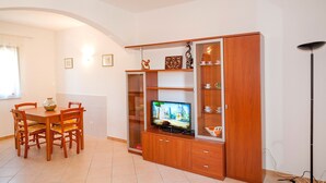 Un coin repas avec une table et des chaises en bois, un téléviseur posé sur un meuble en bois et une lampe sur pied.