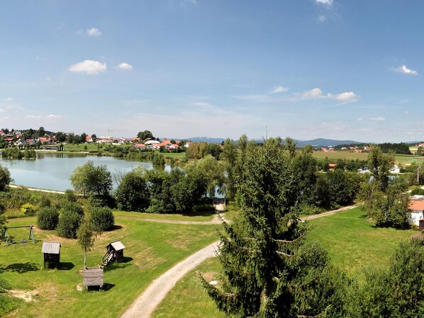A rural landscape with a lake, houses, and a clear sky.