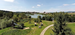 Un parc au bord du lac, doté d’une aire de jeux, de sentiers pédestres et offrant une vue sur un petit village situé au loin.