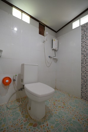 Une salle de bain équipée de toilettes, d’une douche et d’un porte-rouleau de papier toilette.