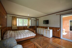 Relax in this serene bedroom with a large bed, glass coffee table, and TV, plus access to an outdoor deck.