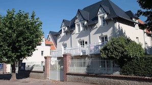 Um edifício de dois andares com fachada branca, telhado escuro e entrada gradeada.