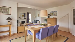 A dining area with a wooden table and purple chairs, a lamp, and a mirror on the wall.