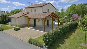 A two-story house with a covered porch, a gravel driveway, and a well-maintained garden.