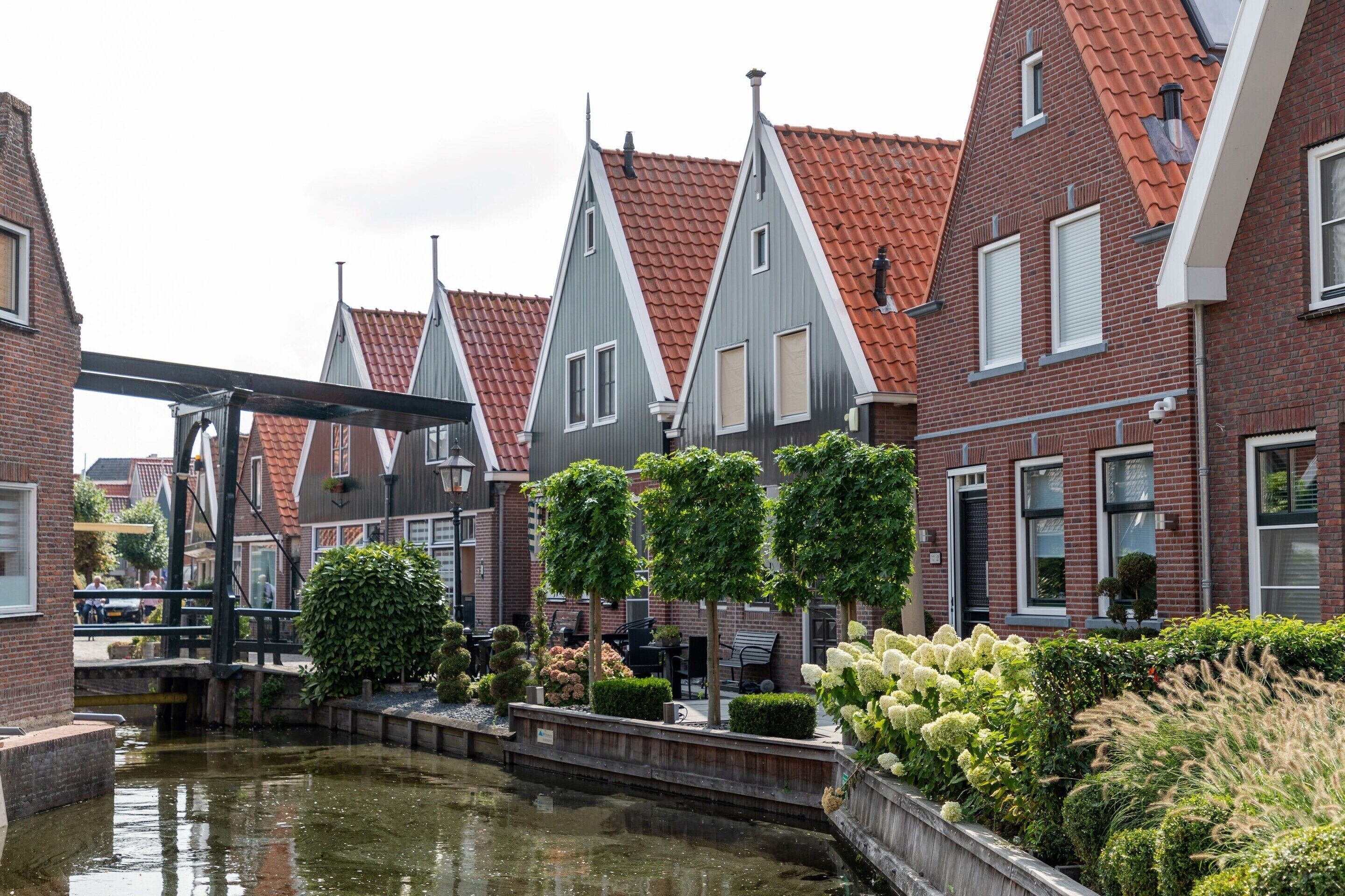 A canal-side building with a traditional design, featuring a waterway, brick walls, and a wooden bridge.