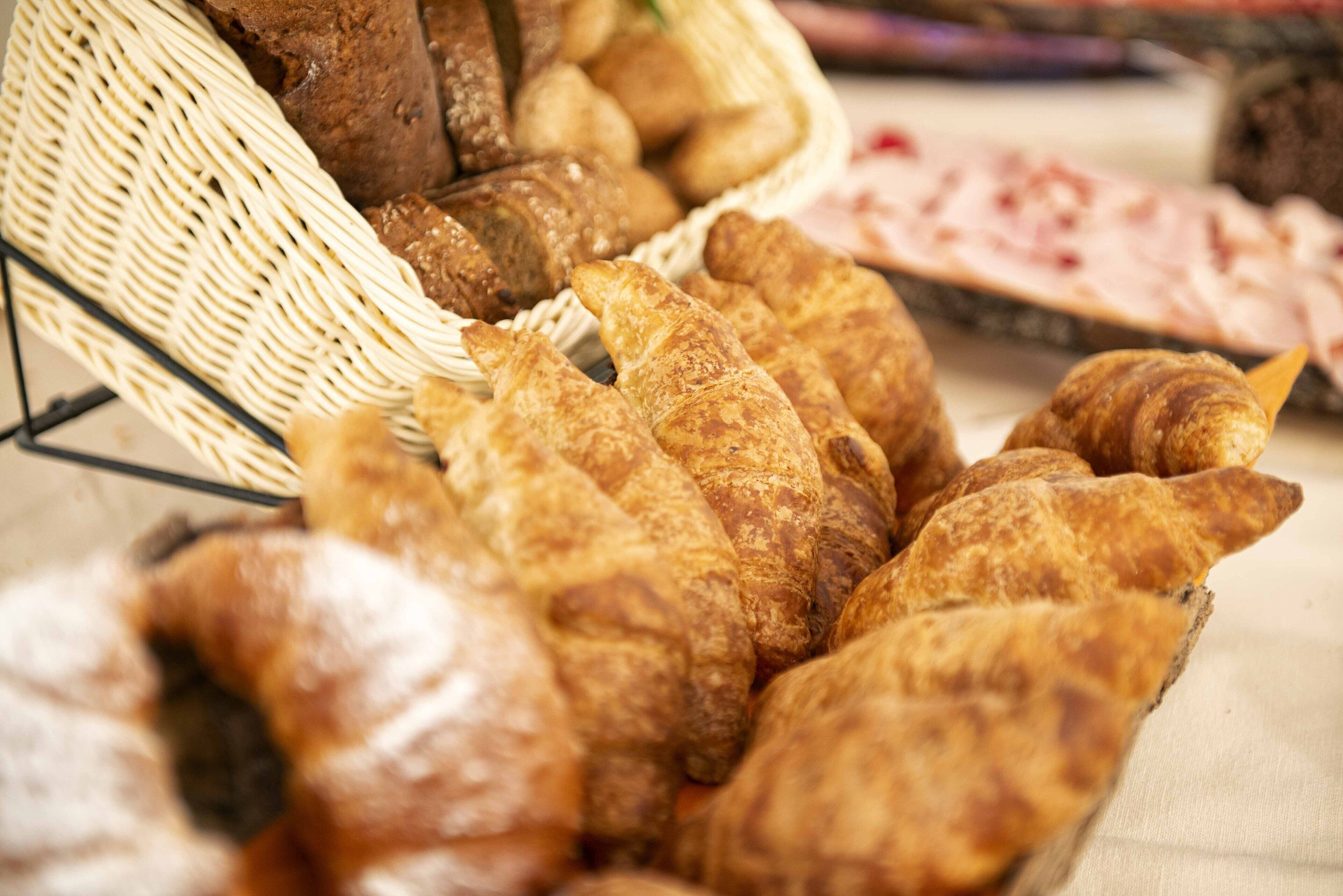 A basket filled with various types of bread, including croissants and baguettes.