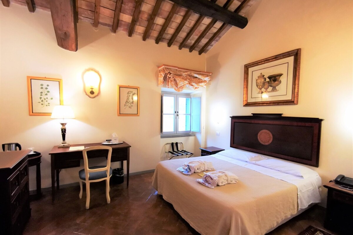 Une chambre d’hôtel avec un lit, un bureau, une chaise et une fenêtre avec des rideaux.