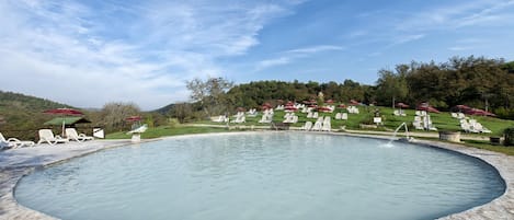 Una piscina cubierta, una piscina al aire libre, sombrillas, tumbonas