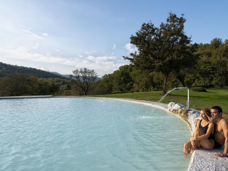 Una piscina techada, una piscina al aire libre, sombrillas