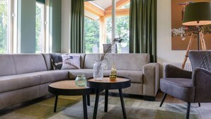 Ein modernes Wohnzimmer mit einem Ecksofa, zwei runden Couchtischen, einem Beistelltisch und einer Stehlampe.