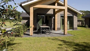 Ein modernes Haus mit überdachter Terrasse, Ziegelaußenwand und großem Fenster.
