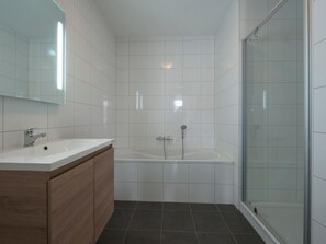 A modern bathroom with a white sink, vanity, and a glass-enclosed shower area.