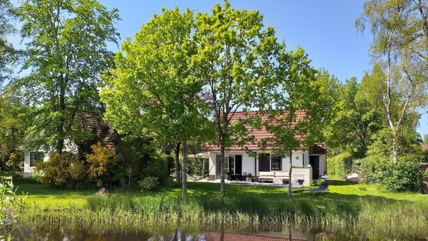 A house with a red roof, surrounded by lush greenery and a pond. - Spacious Home with Garden near Langweerder Wielen (Sint Nicolaasga)