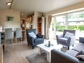 Ein modernes Wohnzimmer mit Essbereich, einer Küche im Hintergrund und großen Schiebeglasüren zum Garten.