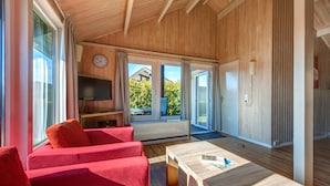 Une chambre moderne avec des murs en bois, une grande fenêtre, un téléviseur et des sièges rouges.