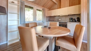Une cuisine moderne avec des meubles blancs, une table ronde en bois et des chaises en cuir.
