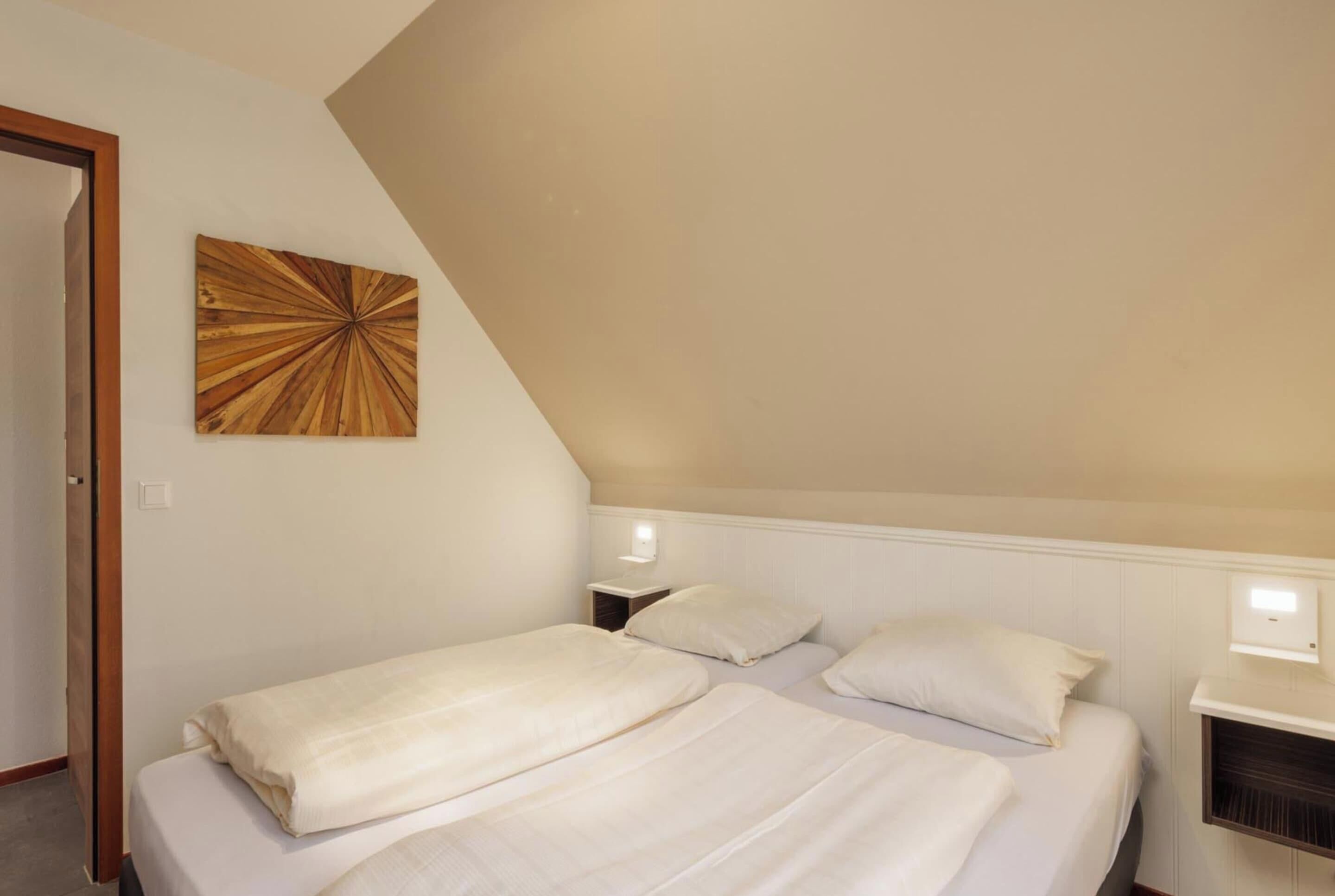 A bedroom with two beds, a wooden artwork on the wall, and bedside lamps.