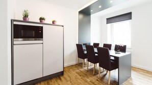 A modern kitchen with a built-in microwave and oven, a dining area with a table and chairs, and a window providing natural light. - Snug Apartment With Balcony (Eisenerz)