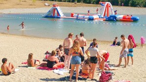 Une plage avec des structures gonflables et des gens qui se détendent sur le sable.
